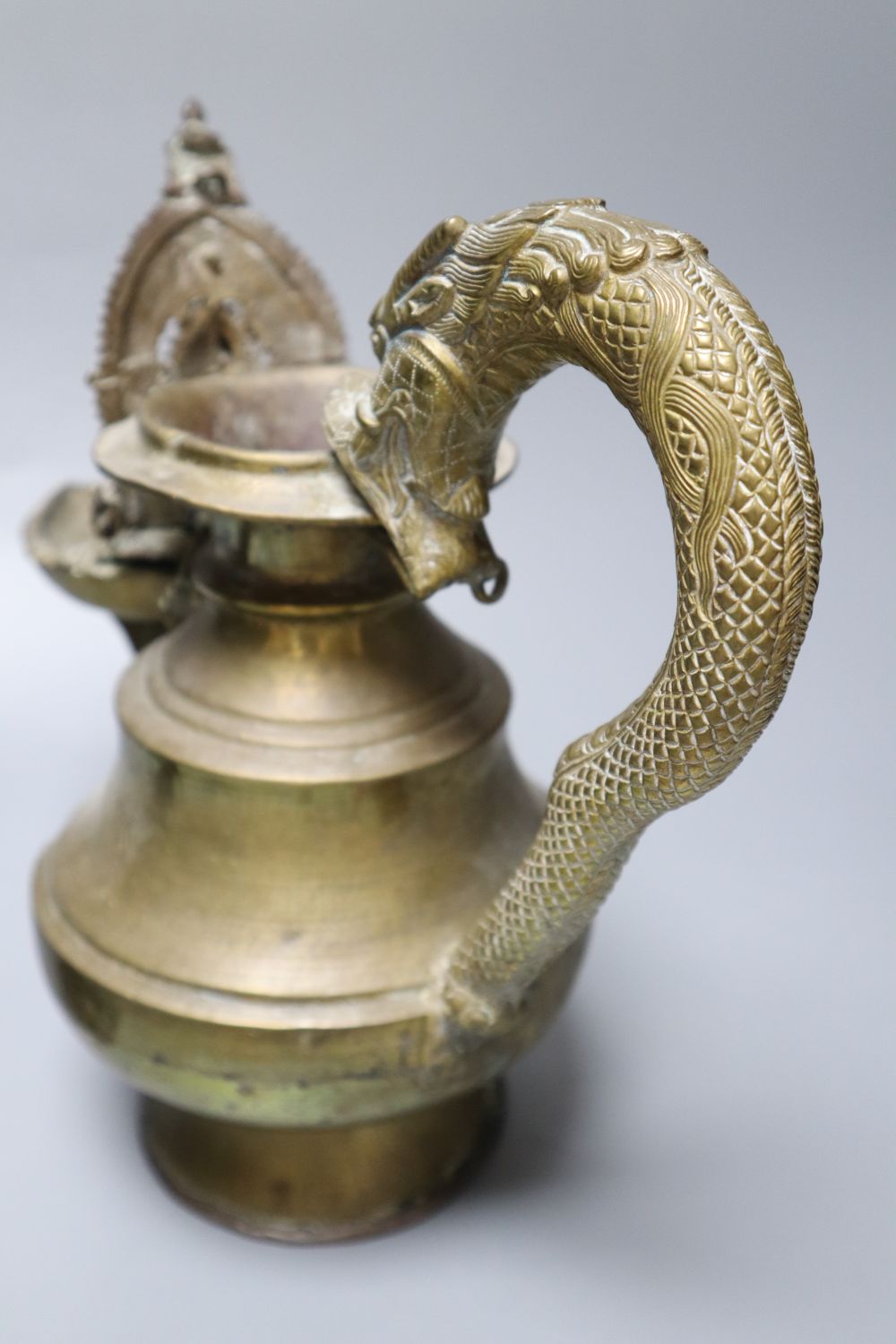 A Himalayan Buddhist brass lamp/ewer with related ladle, 26cm, 19th/20th century and a carved black mineral Chinese stone figure